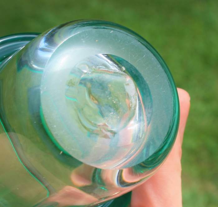 A pontil mark indicates that the piece was hand blown & finished on a pontil rod. Pictured: the pontil mark on the bottom of a Blenko drinking glass.