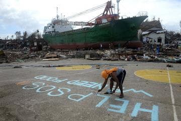 With a large ship washed away inland at the background, a victim writes on the ground asking for help hoping someone from above would see their desperation after Yolanda left the city in ruins...