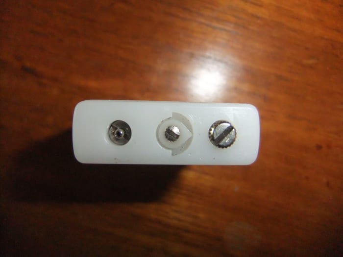 The bottom of the lighter, showing (from left) the butane refill valve, the small screw which controls how strong the flame is, and the screw which holds the flint in place