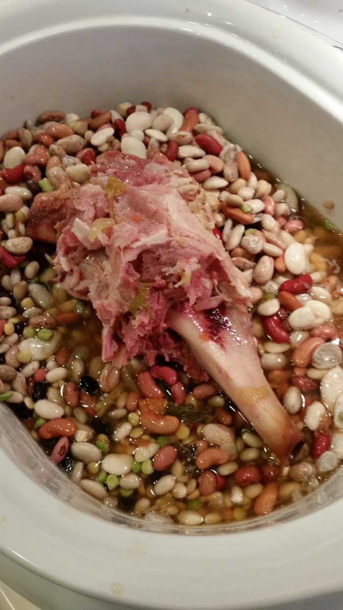 Place the beans and the ham bone in the slow cooker. There are bits of meat and fat clinging to the bone. These will flavor the soup and provide protein.