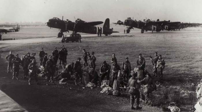 3. Platoon, 21st Ind. Parachute Coy. emplane at Fairford, Gloucester. Behind them are Short Stirling Bombers taken from bombing duties, assigned to tow gliders - vertical stripes were added to fuselages and wings for recognition as Allied aircraft