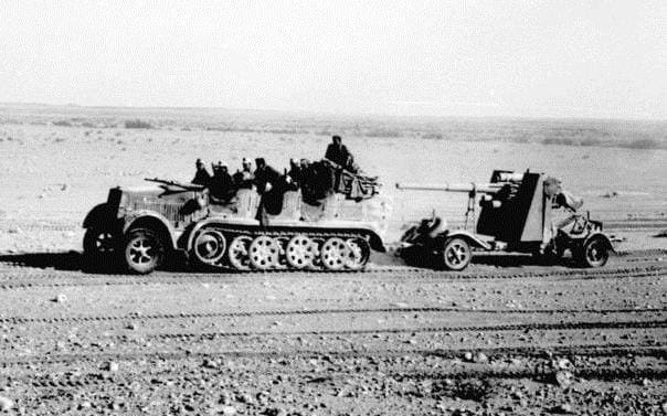 In North Africa, 8.8cm Flak 18 towed behind a Sd.Kfz. 7, with its side outriggers lifted for transport visible behind the gun shield.