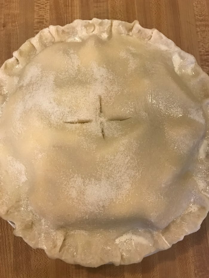 Brush the top crust with cream, sprinkle on the sugar then cut vents. Or you could prick the top with a fork. Granny would say to make it look like a little bird had hopped across the pie.