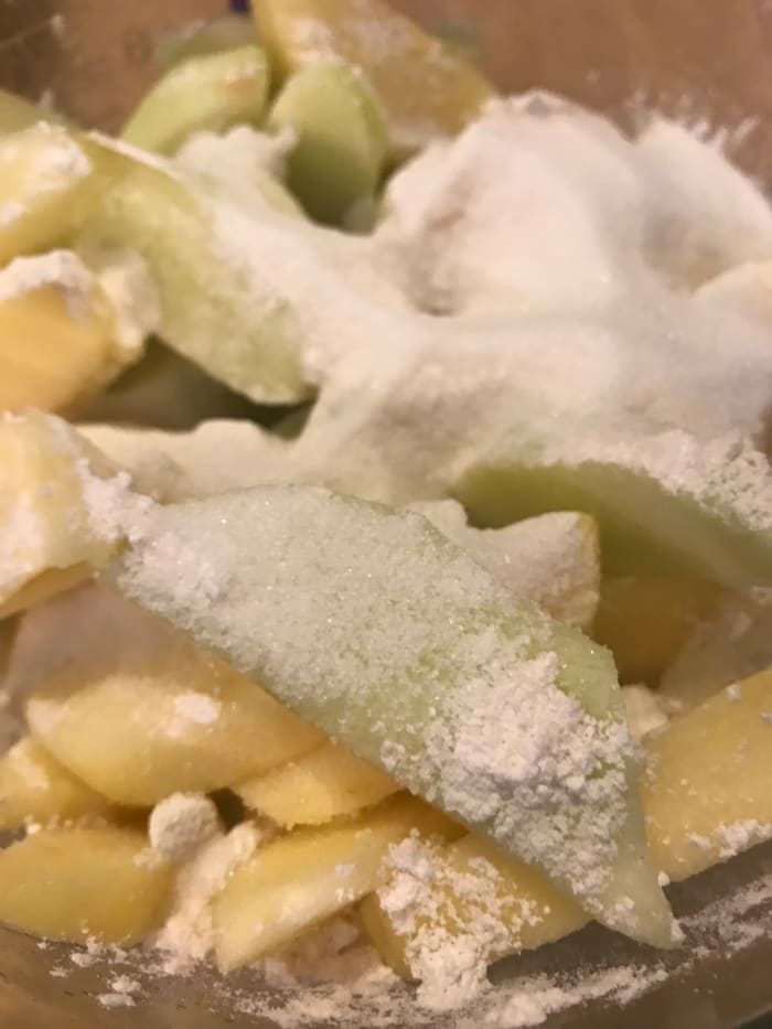 The sugar enhances the sweetness of course, and the flour helps thicken the juices that will cook out of the apples.