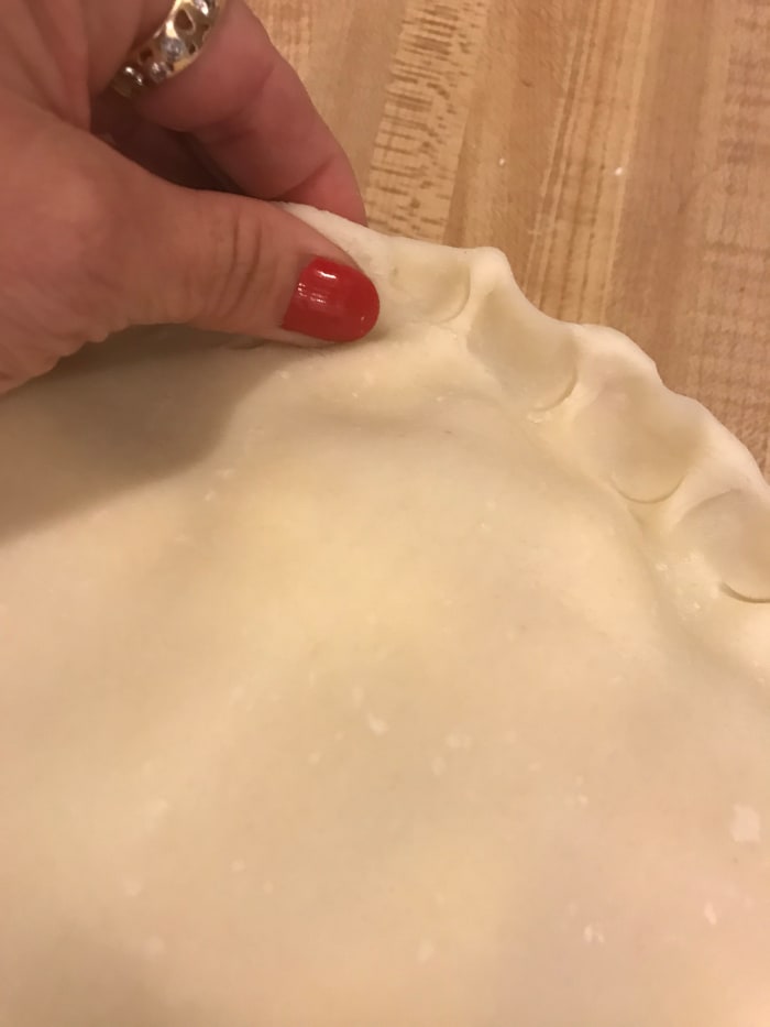 Crimping the edges does a couple of things. It's pretty - and pretty food tastes better. But it also seals the juices into the pie, so there's less chance of spillover in the oven.