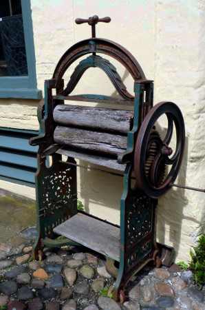 You can see the handle that controls the width of the space between the rollers, on the top of the mangle