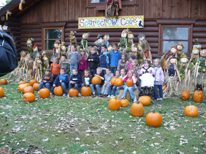A classroom gets their photo taken in front of Scarecrow Cove during their field trip to the Papa's Pumpkin Patch