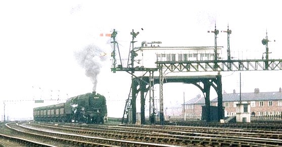 Box on stilts :9F 2-10-0 and Iron Ore bogies from Tyne Dock for Consett pass Green Lane near Washington, Co. Durham. Note the signal gantry and long twin bracket this side of the elevated box.