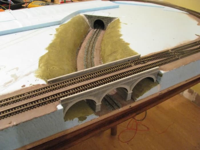 Embed the viaduct, get the railway done first, surroundings later. You'll have picked up a few tips by the time you've got that far, changed your mind or turn it into plain fields with hedging. Choices are infinite, tractors, combines, livestock...