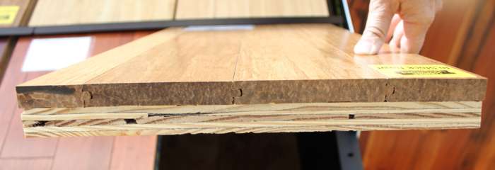 This is the edge of a flooring sample of solid strand bamboo mounted on a piece of plywood.