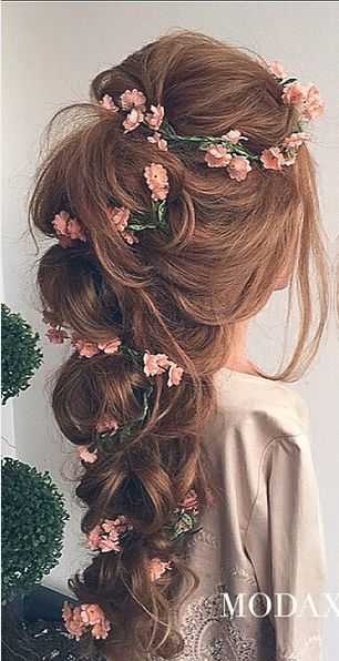 Most romantic bridal hairdo with thick loose braid and artfuly planted pink tiny flowers and green wines.
