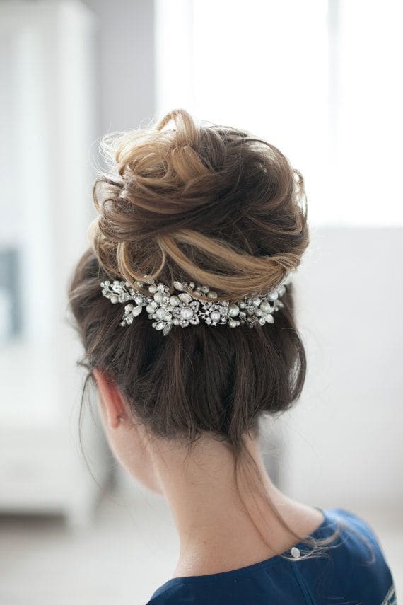 high hair bun which is a little wispy with a gorgeous piece of hair jewellery pinned underneath the bun
