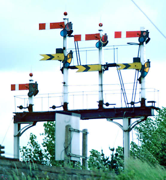 A short gantry of semi-distant semaphore signals for one direction of travel, i.e., home signal above distant