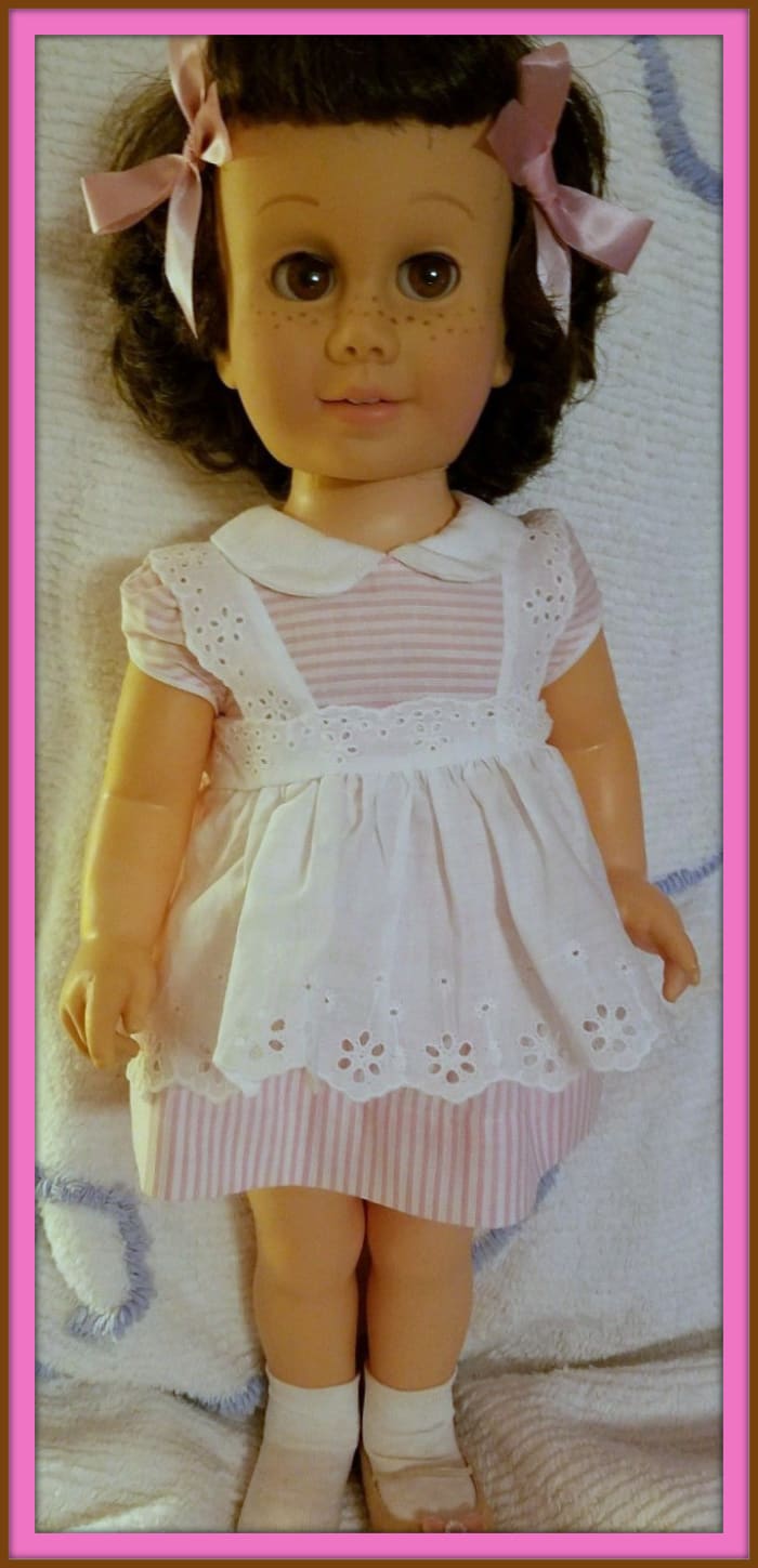 She is a rare brunette, with a bob hair cut, she has matching brown eyes. She is in her MINT original pink pin striped outfit with right shoe missing.