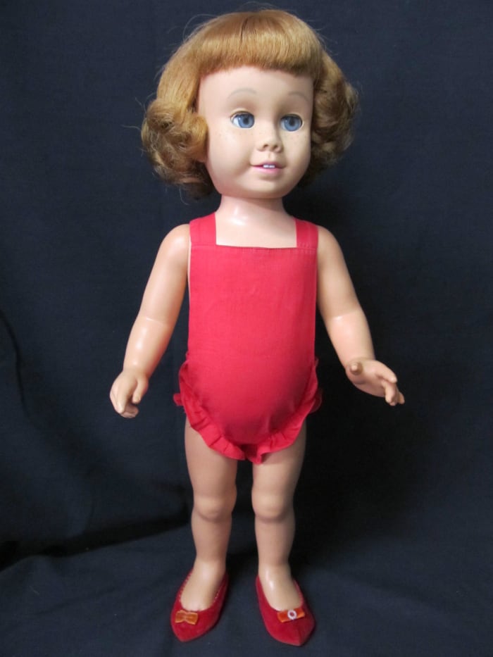 She has clean, shiny strawberry blonde hair in a "flip" hair style (hair definitely has a reddish cast, see outdoor picture), blue sleep eyes with all lashes intact, the usual freckles, pink lips and 2 teeth.