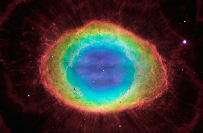 The blue gas in the nebula's center is actually a football-shaped structure that pierces the red doughnut-shaped material. Hubble also uncovers the detailed structure of the dark, irregular knots of dense gas embedded along the inner rim of the ring.