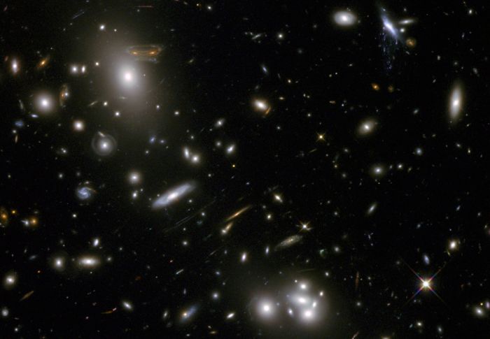 The gravitational field surrounding this massive cluster of galaxies, Abell 68, acts as a natural lens in space to brighten and magnify the light coming from very distant background galaxies. Like a funhouse mirror, lensing creates a fantasy landscap