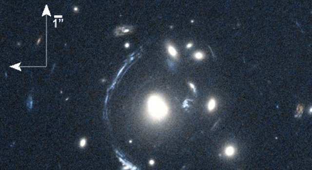 Smeared and Magnified Galaxy The young galaxy SDSS090122.37+181432.3, also known as S0901, is seen here as the bright arc to the left of the central bright galaxy. The distorted view of S0901 is caused by gravitational lensing, resulting from one or