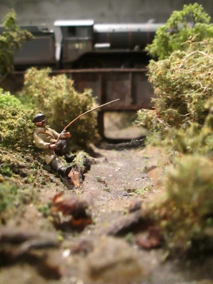 ... Meanwhile back down by the bridge an angler hopes for a catch - let's hope it's not old railwayman's boots he lands. (Figure provided by a friend some years ago)