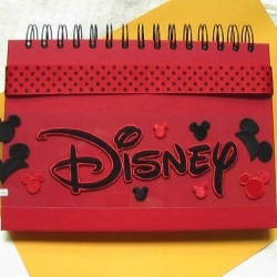 A work in progress: place your Disney stickers and ribbon decorations on the cover of your memory book before you glue them in place. You will be happy with the results if you do.