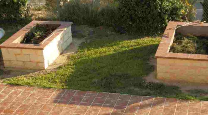 the same two raised bed gardens later in the season (the grass has grown back) partially filled with garden waste to make compost