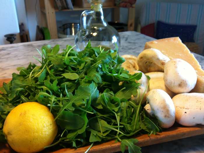 Ingredients arugula, Champignon mushrooms, Parmesan cheese, lemon and olive oil