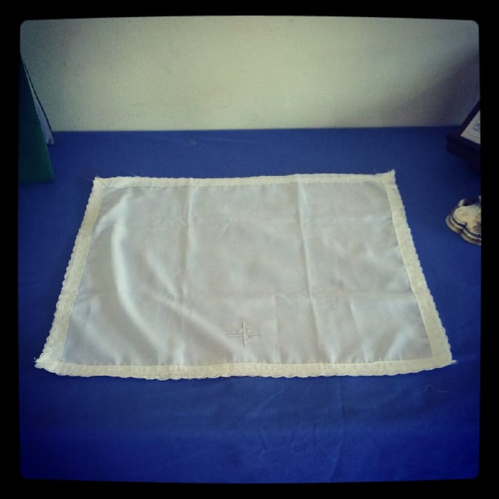 Step 1: Lay out the Corporal. If your corporal has a cross stitched onto it, the cross must be placed closest to the Celebrant.
