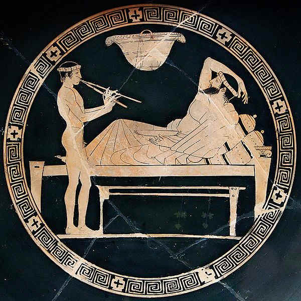 Banquet scene: man reclining on a bench and youth playing the aulos. Tondo of an Attic red-figure cup, ca. 460 BC–450 BC.
