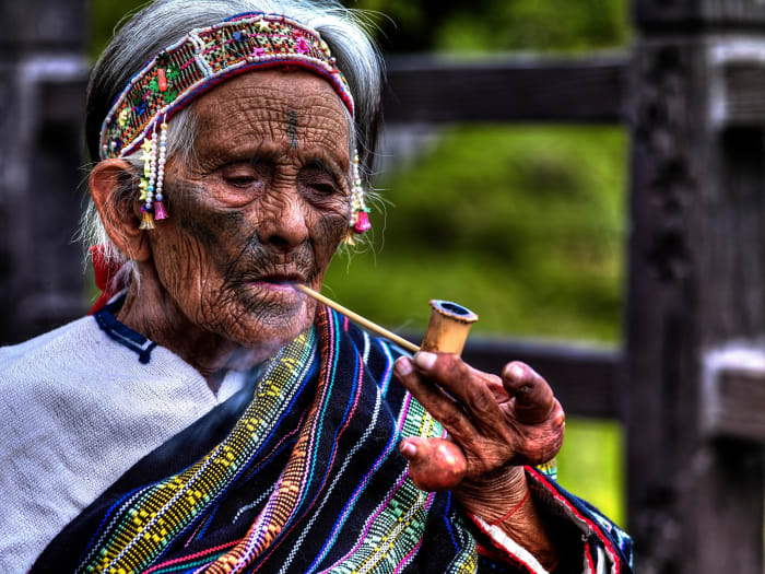 Elderly member of the Atayal tribe smoking a pike. Facial tattooing is one of the most important customs of this tribe - a custom which dates back over 1,400 years. They are used to indicate one's place within the tribe.