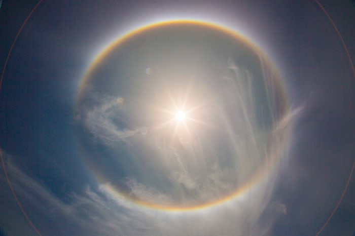 This Sun Halo clearly shows the rainbow-like circle that is indicative of Sun Halos and lens flares that might be mistaken as planets around the Sun. Science explains this as caused by ice particles in the atmosphere, might there be another cause?