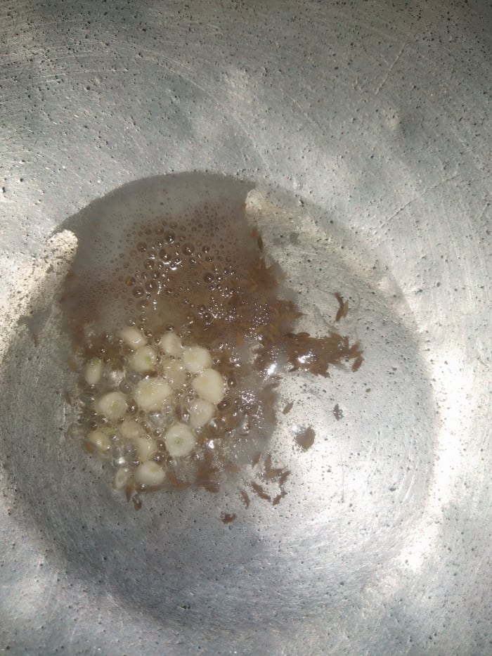 In a pan heat oil, ghee or butter. Add cumin seeds and chopped garlic, saute till raw smell of garlic goes away.