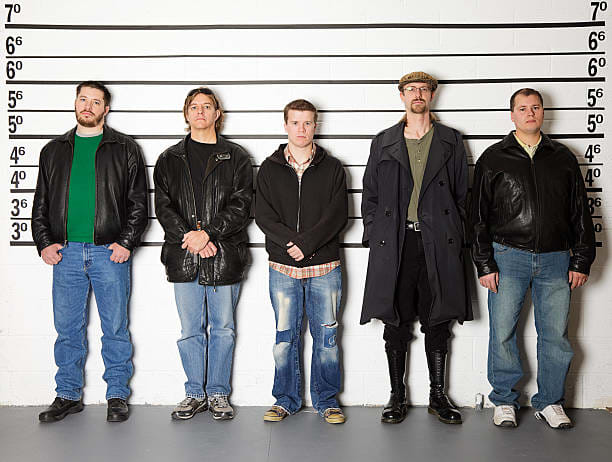 We're all lined up, as different as Goofy and Clint Eastwood. The old biddy coughs and beckons the officer in charge...