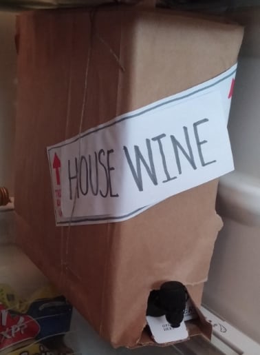 Wrap a box of wine in brown lunch bag paper, slap a "This End Up" label on it and write House Wine. Then tie some twine on so it looks like a moving box.
