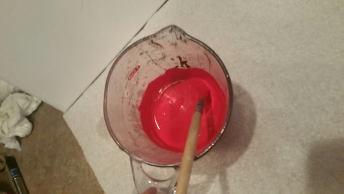 Add about 1/4 cup of paint to your measuring cup along with a couple drops of water. Mix your paint and water (you may need to add more water to get the right consistency) until your mixture is thin enough to where it will move around the bottle.