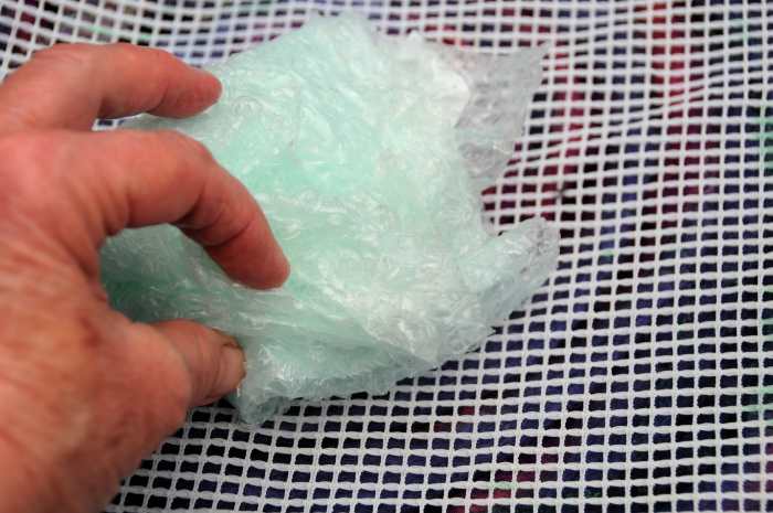 Rubbing the wet fibers below the curtain netting with a piece of folded bubble-wrap. Rub until the fibers no longer move.
