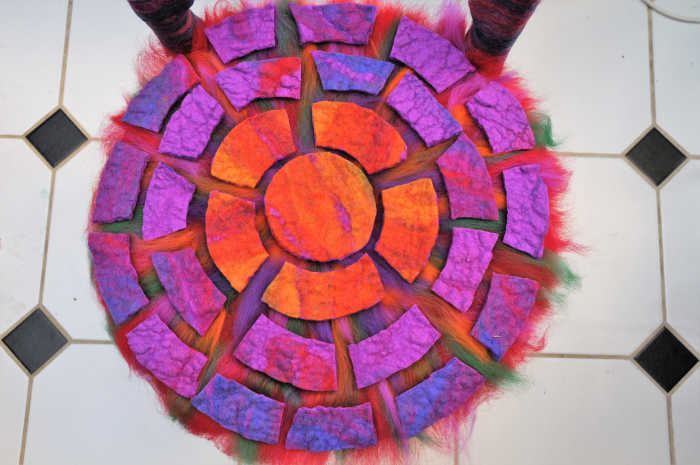 The fibers placed below and between the pre-felted are there to assist attachment of the pre-felted bits to the base of the chair.