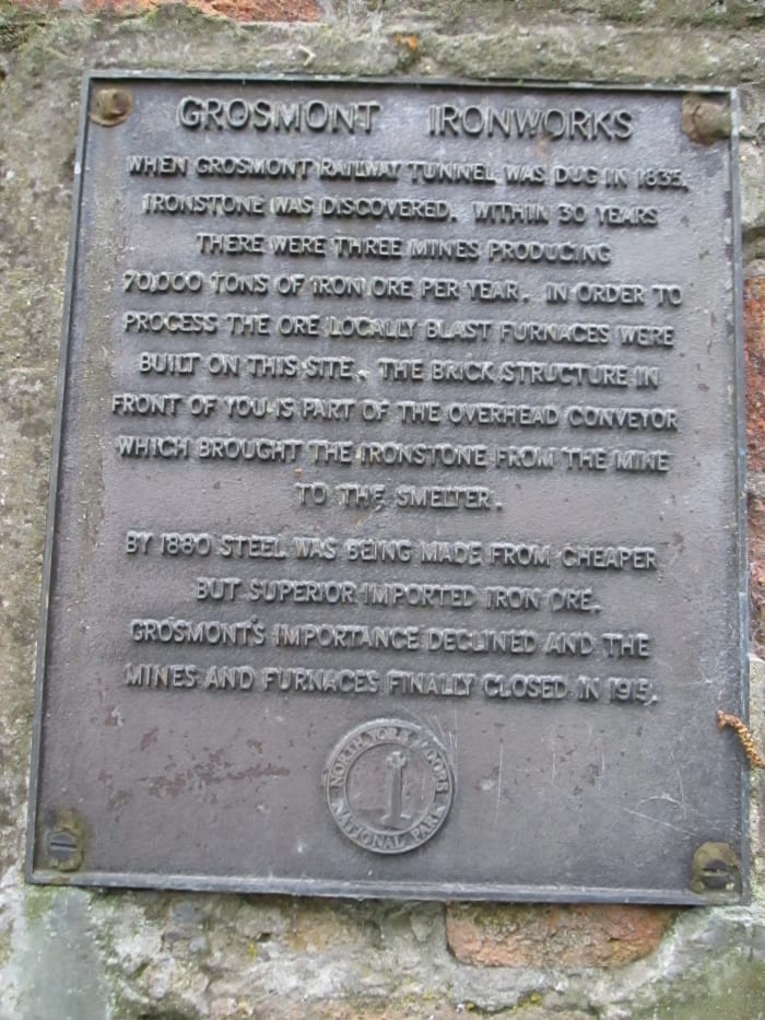 The iron works, commemorated by this plaque, opened late1830s to process ironstone mined nearby in Eskdale after iron was found during digging the original tunnel bore. The site is north of the line to Whitby