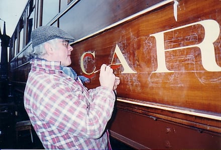 Lettering and numbering is a rewarding, if back-breaking job. A restorer works on a restaurant car waist panel