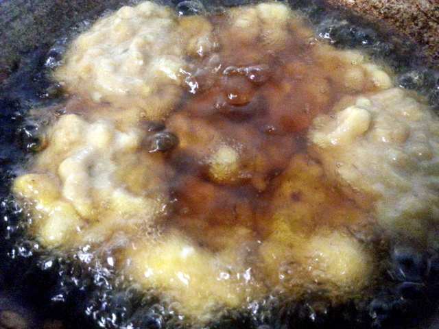 Scoop the cekodok mixture into the wok and fry one side until it is medium brown. You can fry four or five pieces at the same time.