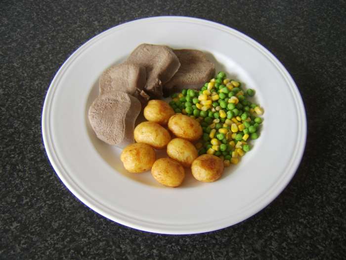 Still warm slices of ox tongue are served with pan roasted baby potatoes and a combination of peas and sweetcorn