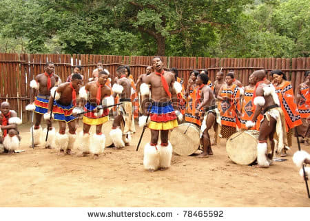 Swazi men and women in the background, in traditional clothes and performing a Swazi traditional dance