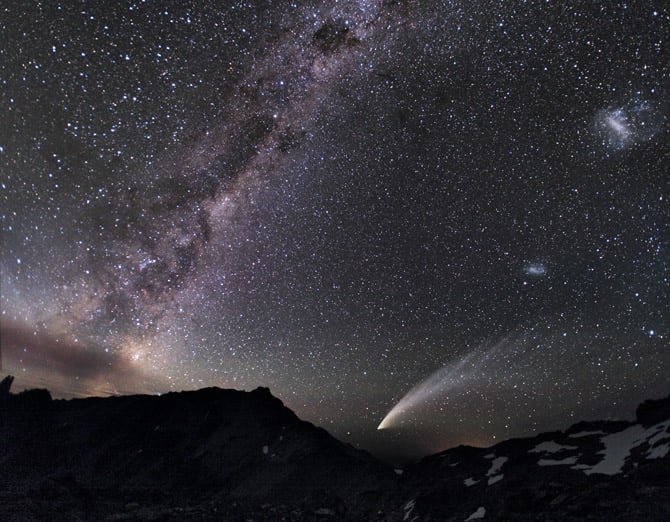 The Magellanic Clouds—two gauzy patches of light (at far right)—share the sky above the Patagonian Andes with a streaking comet and the luminous band of the Milky Way.