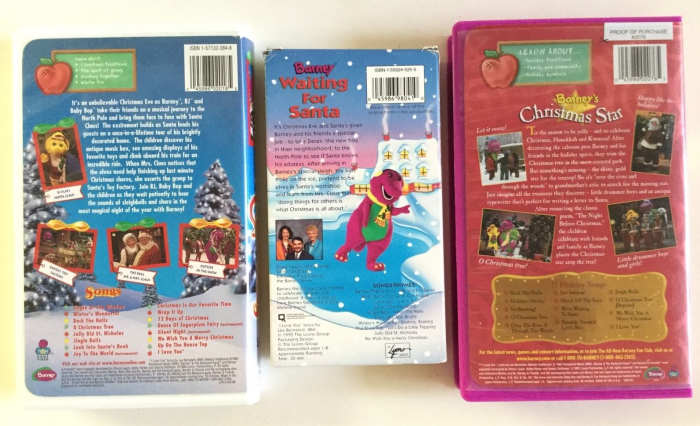 This photo is of the back side of the outside cases of the three Barney Christmas VHS videos, Waiting For Santa, Barney's Night Before Christmas, Star