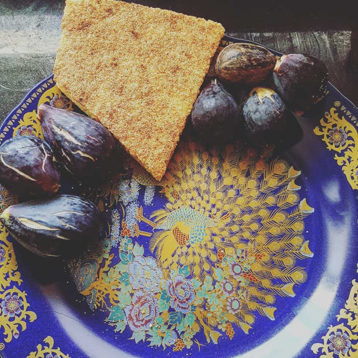 Fresh figs from Kenitra, Morocco, surround a slice of harsha. The plate is adorned with a peacock - a common design found on many platters.