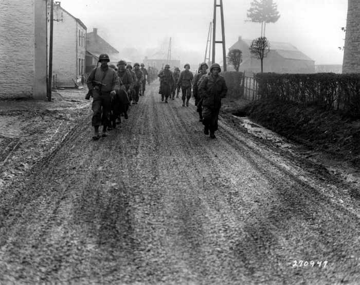 The 28th Infantry Division "Iron Division" walking the streets of Bastogne shattered before the advancing German spearhead some without weapons just four months after their triumphant parade through Paris in the summer of 1944.