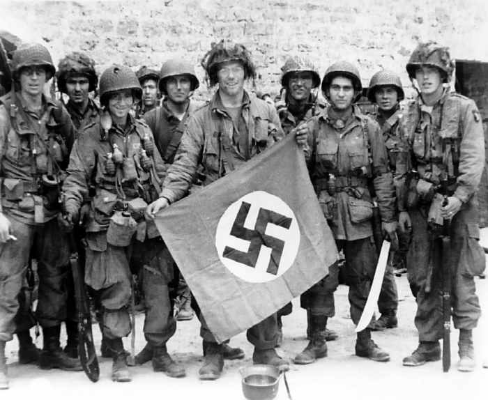 101st Airborne troops posing with a captured Nazi vehicle air identification sign two days after landing in Normandy June 8,1944.