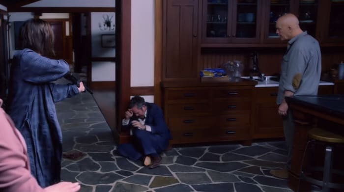 Malorie (Sandra Bullock) and Douglas (John Malkovich) grill Gary (Tom Hollander) at gunpoint when he arrives at the house in 'Bird Box' (2018), a Netflix Original.