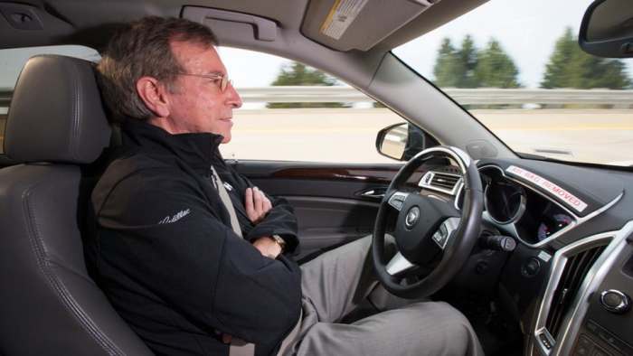 Car with no gads on steering wheel. General Motors’ Super Cruise could allow the car to drive itself on long, monotonous stretches of highway – leaving the driver free to relax.