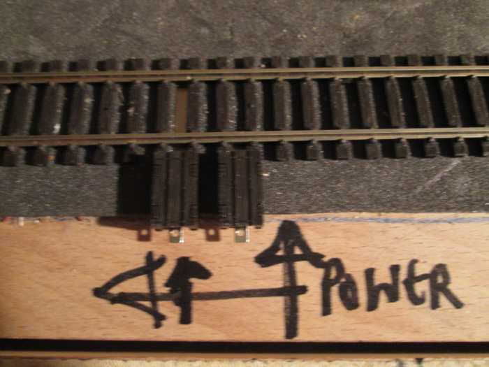 A pair of Peco power clips inserted to 'hold' the underside of the sleeper and rail. They're pulled around and over the edge of the sleeper to keep the power flow steady