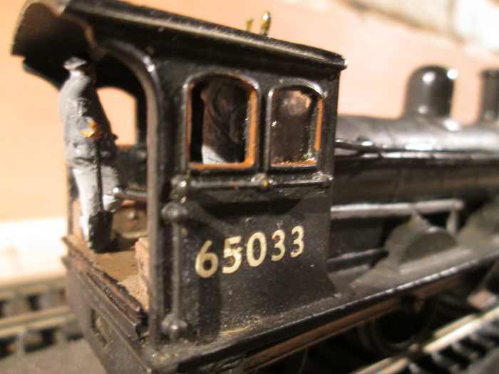 ...And in close-up of the cab. The driver (on this side, lost in shadow) has a hand on the regulator as he looks through his 'porthole' for signals. The fireman to his left nonchalantly takes a breather from topping up the grate.